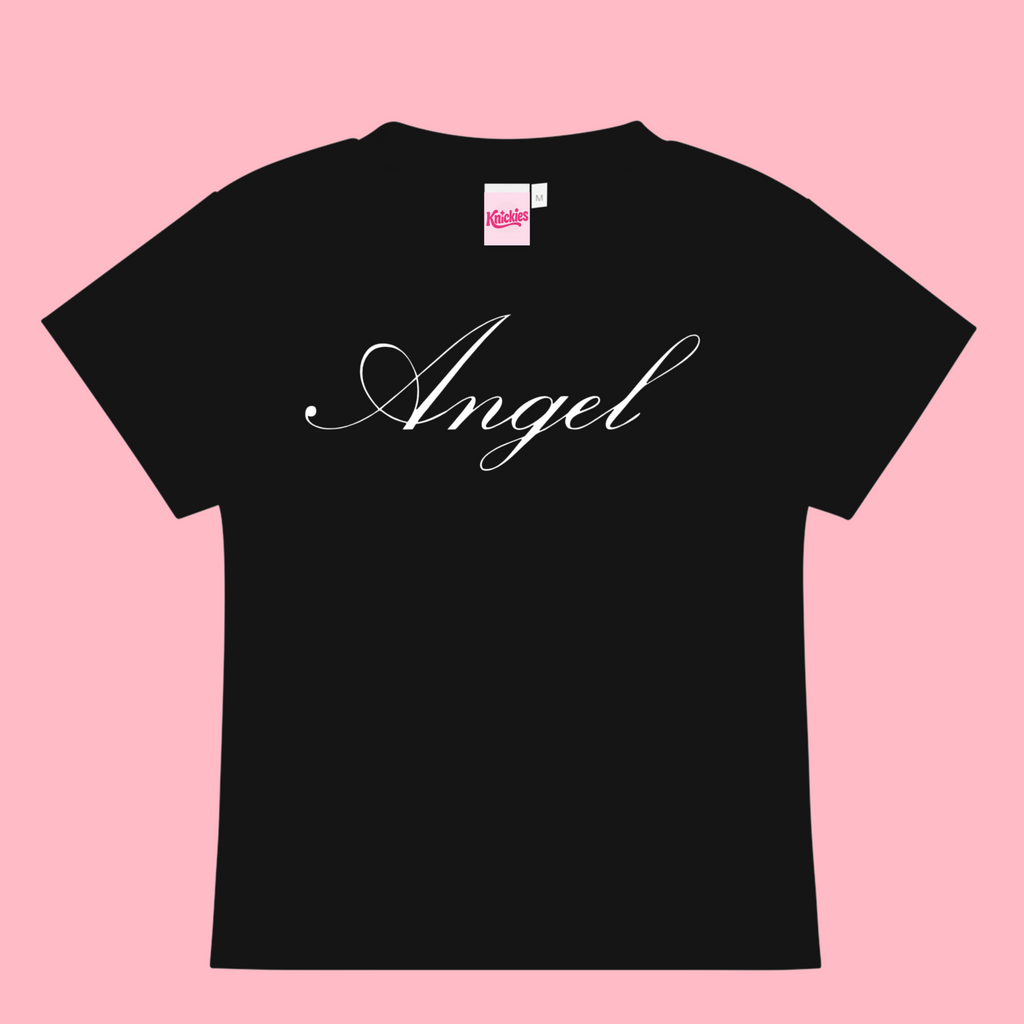 Black t-shirt with 'Angel' printed on it against a pink background
