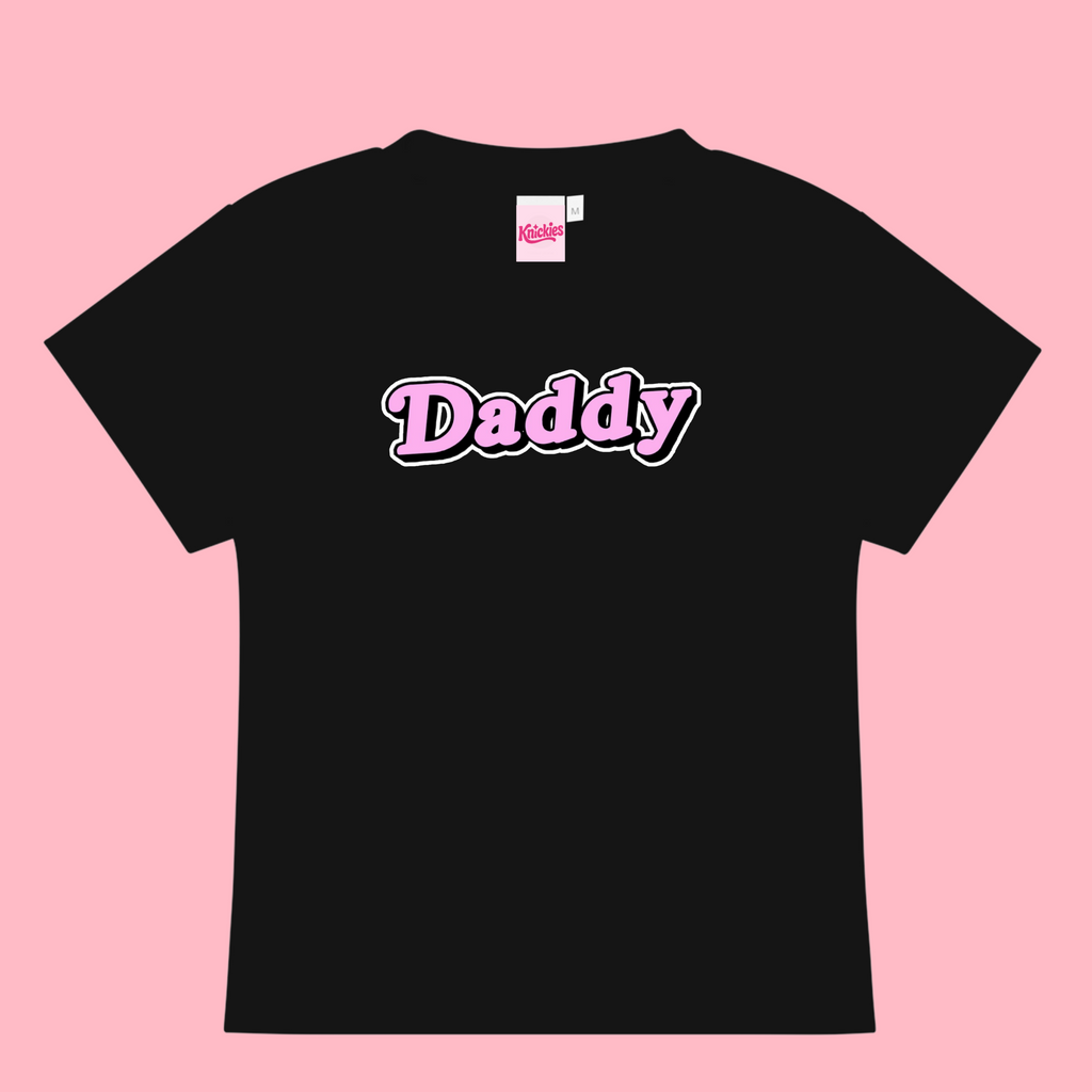 Black t-shirt with 'Daddy' printed on it against a pink background