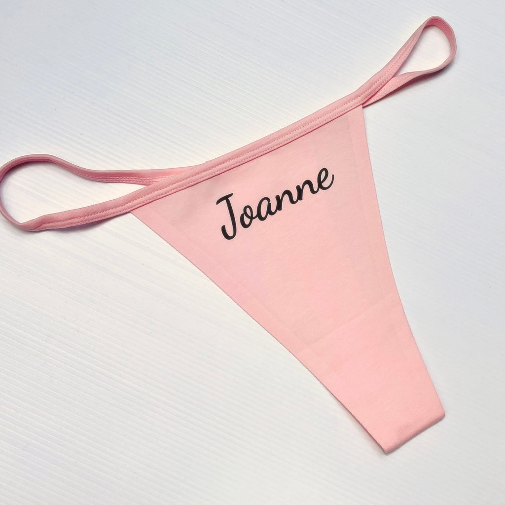 Pink garter belt with 'Joanne' embroidery on a white background