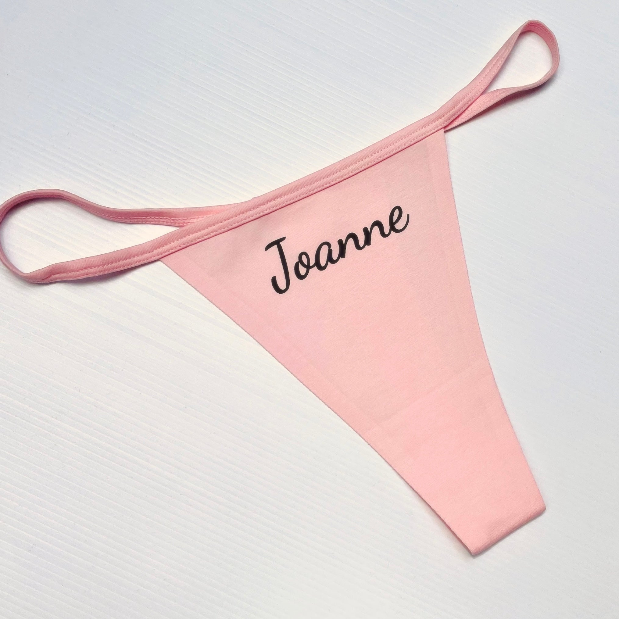 Pink garter belt with 'Joanne' embroidery on a white background